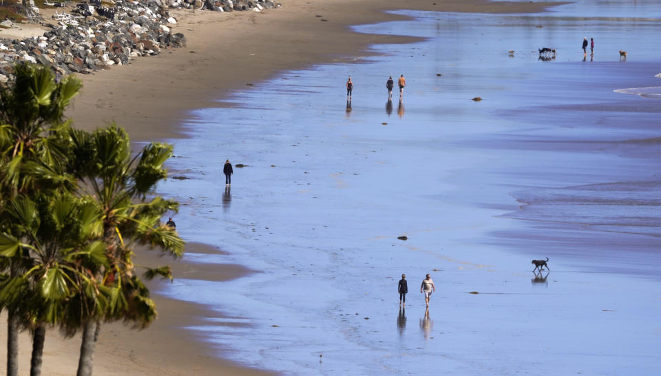 People walks along Zuma Beach, Monday, March 23, 2020, in Malibu, Calif. Officials are trying to dissuade people from using the beaches after California Gov. Gavin Newsom ordered the state's 40 million residents to stay at home indefinitely. His order restricts non-essential movements to control the spread of the coronavirus that threatens to overwhelm the state's medical system. (AP Photo/Mark J. Terrill)