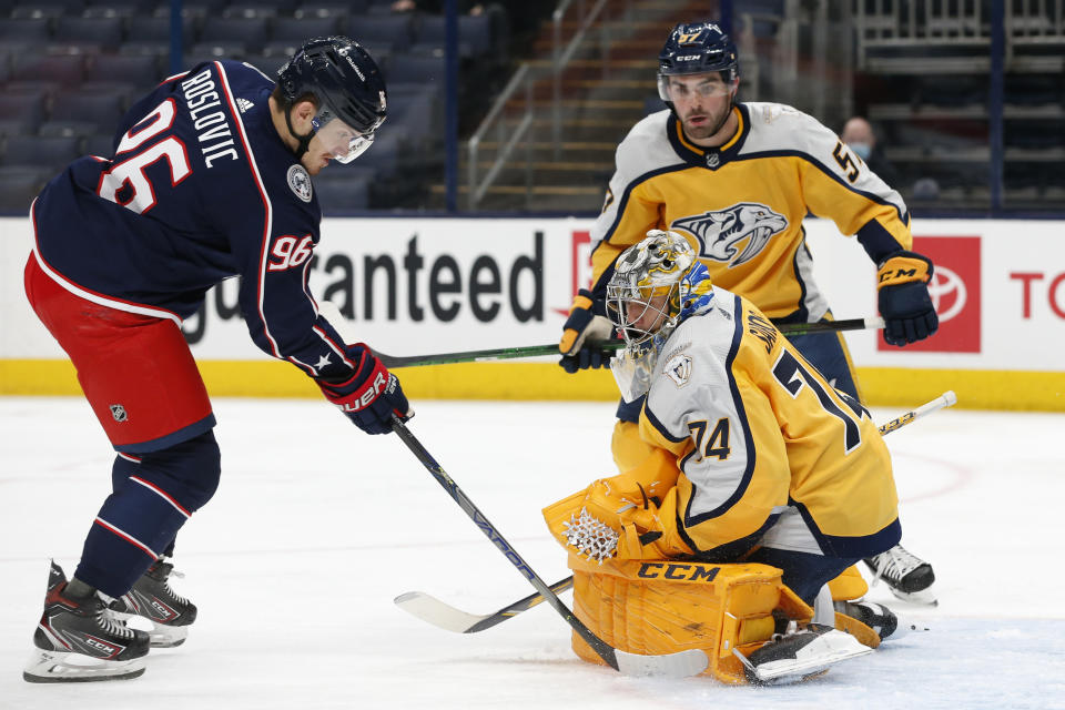 Nashville Predators' Juuse Saros, front right, makkes a save against Columbus Blue Jackets' Jack Roslovic as Dante Fabbro looks for the rebound during the second period of an NHL hockey game Thursday, Feb. 18, 2021, in Columbus, Ohio. (AP Photo/Jay LaPrete)