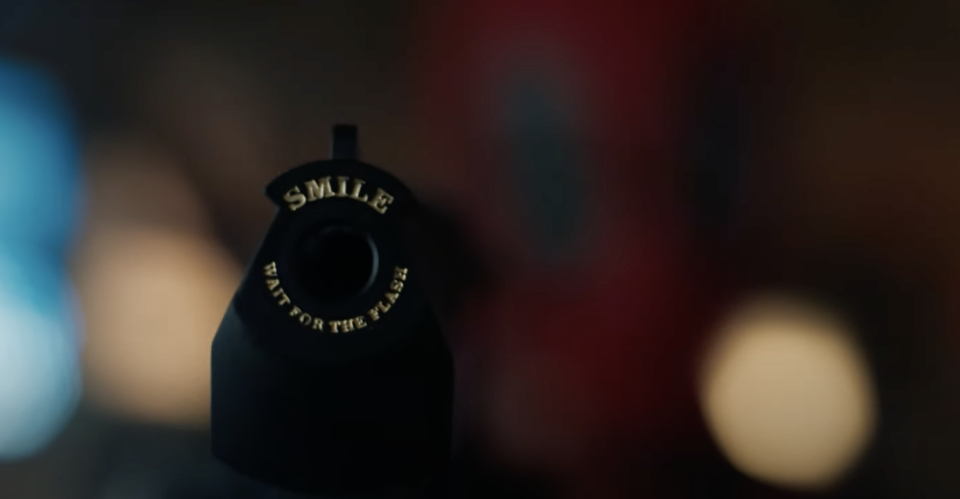 Close-up of a camera with the text "SMILE WAIT FOR THE FLASH" on a blurred background