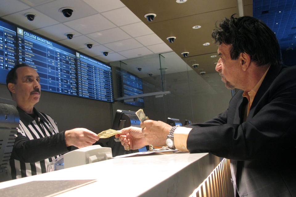 FILE - In this Jan. 29, 2020, file photo, a gambler makes bets on the upcoming Super Bowl at Bally's casino in Atlantic City N.J. The coronavirus pandemic could lead to a quicker expansion of sports betting and internet gambling in the U.S. as states deal with huge budget deficits and look for new tax revenue wherever they can find it.(AP Photo/Wayne Parry, File)