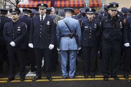 Law enforcement officers stand, with some turning their backs, as New York City Mayor Bill de Blasio speaks on a monitor outside the funeral for NYPD officer Wenjian Liu in the Brooklyn borough of New York January 4, 2015. REUTERS/Shannon Stapleton