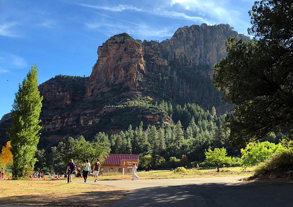 In this 2018 photo visitors walk at the entrance to Slide Rock State Park near the town of Sedona, Ariz. The sleepy Arizona town of Sedona has long been a refuge for hikers, romantics and soul searchers. (AP Photo/Joseph Gedeon)