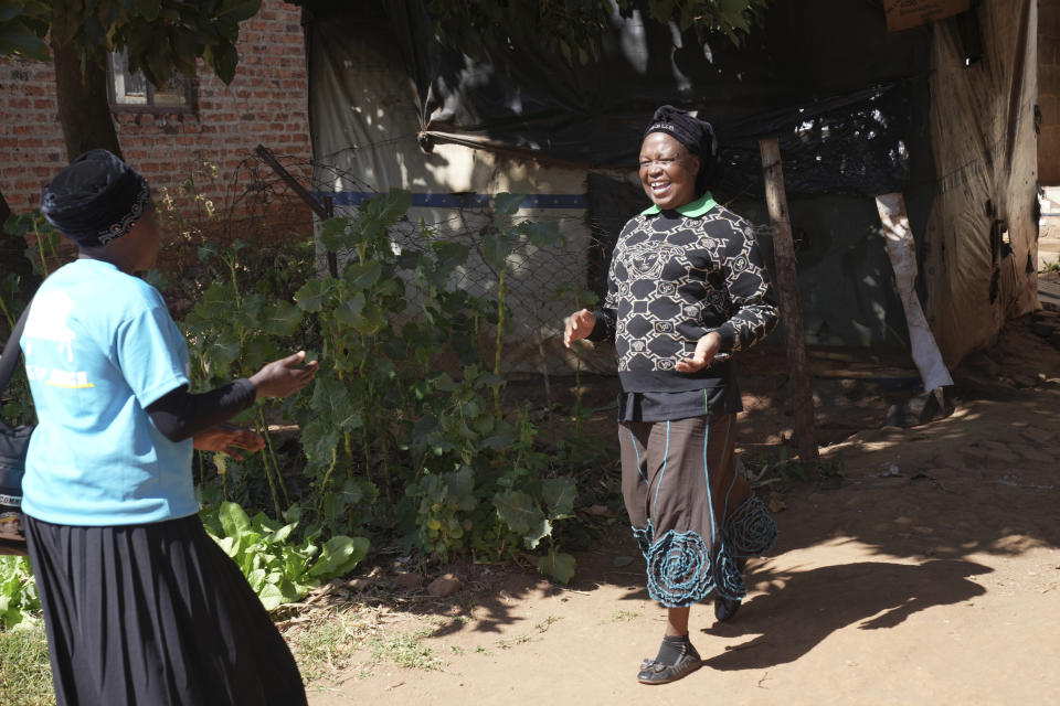 Siridzayi Dzukwa, a grandmother, left, meets up with Tambudzai Tembo outside her house in Hatfcliffe on the outskirts of the capital Harare, Zimbabwe, Wednesday, May 15, 2024. In Zimbabwe, talk therapy involving park benches and a network of grandmothers has become a saving grace for people with mental health issues. Now the concept is being adopted in parts of the United States and elsewhere. (AP Photo/Tsvangirayi Mukwazhi)