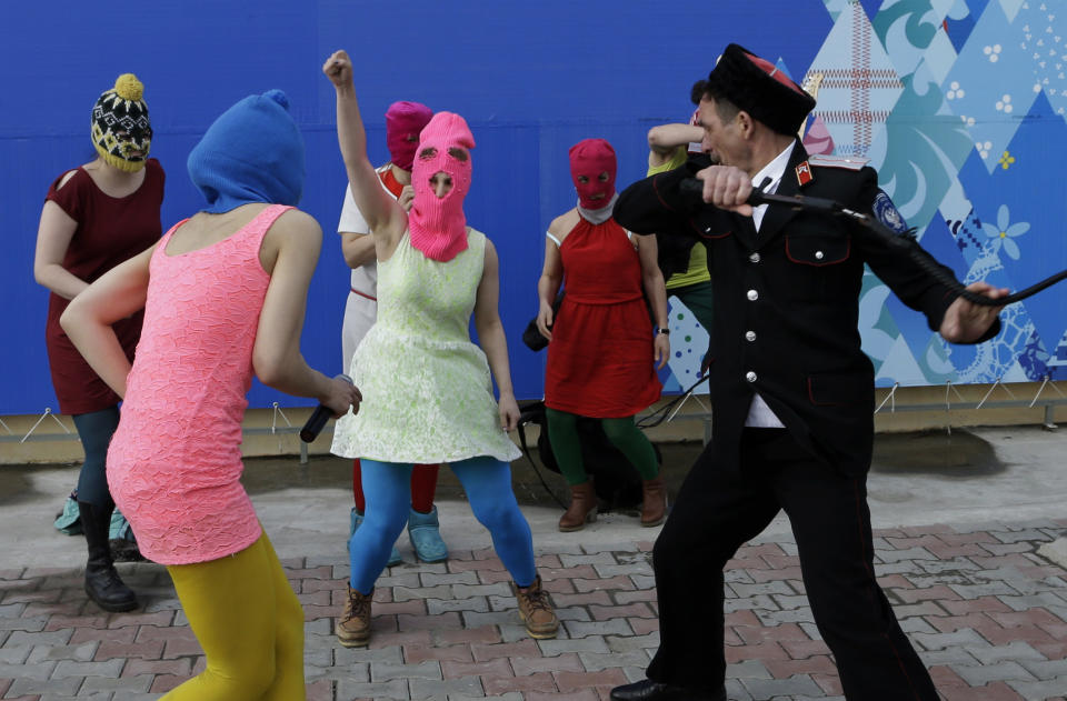 Members of the punk group Pussy Riot, including Nadezhda Tolokonnikova in the blue balaclava and Maria Alekhina in the pink balaclava, are attacked by Cossack militia in Sochi, Russia, on Wednesday, Feb. 19, 2014. The group had gathered in a downtown Sochi restaurant, about 30km (21miles) from where the Winter Olympics are being held. They ran out of the restaurant wearing brightly colored clothes and ski masks and were set upon by about a dozen Cossacks, who are used by police authorities in Russia to patrol the streets. (AP Photo/Morry Gash)