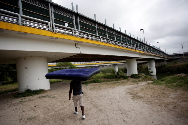 A migrant from Haiti carries a mattress as local authorities prepare to respond to the coronavirus disease (COVID-19) outbreak, in Matamoros