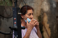 A woman removes her protective face mask and smokes a cigarette at a food market in the central Israeli town of Ramla near Tel Aviv, Wednesday, July 15, 2020. As Israel grapples with a spike in coronavirus cases, it has begun to impose restrictions. (AP Photo/Oded Balilty)