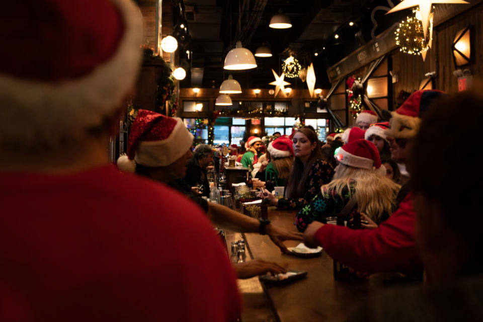 People dressed in Santa Claus costumes order drinks at Mustang Harry's during SantaCon in New York City. (Photo by David Dee Delgado/Getty Images)