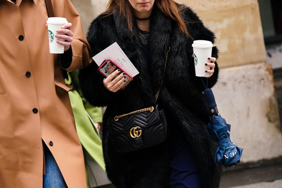 paris, france march 02 a guest l wears a light brown leather coat, blue jeans a guest r wears necklaces, a black fur coat, a black gucci bag, a navy blue dress, holds a cup from starbucks coffee, outside giambattista valli, during paris fashion week womenswear fallwinter 20202021, on march 02, 2020 in paris, france photo by edward berthelotgetty images