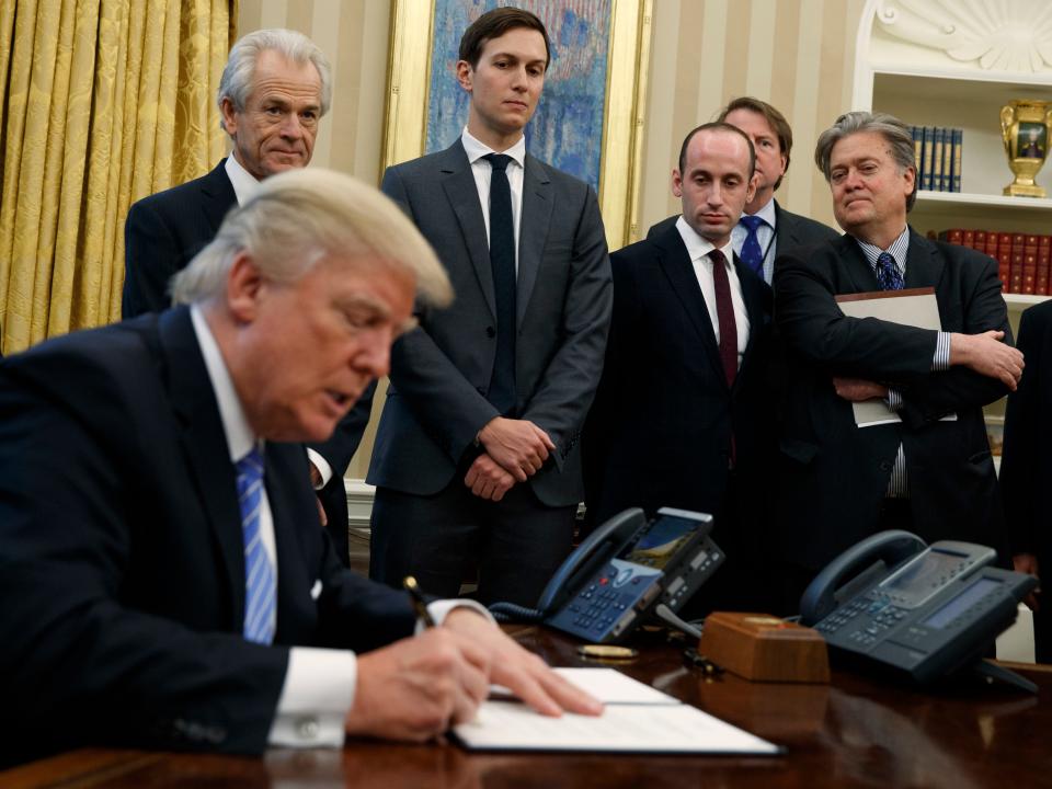 In this Jan. 23, 2017 file photo, White House chief strategist Steve Bannon, right, and others, watch as President Donald Trump signs an executive order in the Oval Office of the White House in Washington.