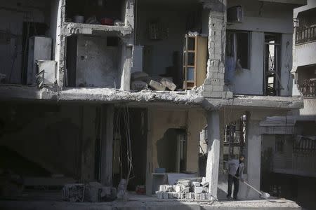 A man clears rubble from his damaged house in Douma, eastern al-Ghouta, near Damascus, December 11, 2014. Picture taken December 11, 2014. REUTERS/Bassam Khabieh