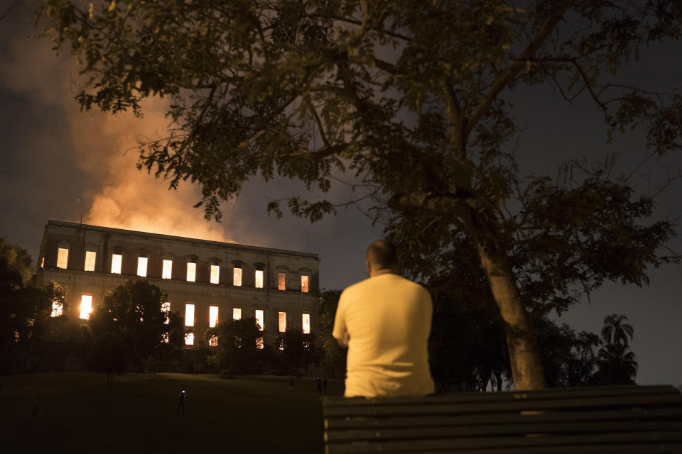 A man watches as flames engulf the 200-year-old National Museum of Brazil, in Rio de Janeiro, Sunday, Sept. 2, 2018. According to its website, the museum has thousands of items related to the history of Brazil and other countries. The museum is part of the Federal University of Rio de Janeiro. (AP Photo/Leo Correa)