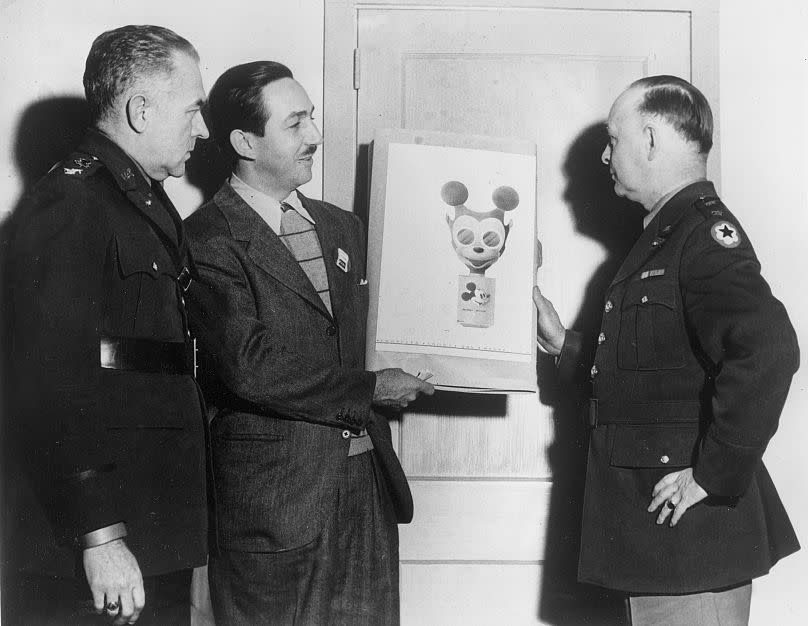 Walt Disney, second from left, hands over his sketch of a Mickey Mouse gas mask to Maj. Gen. William Porter, right, in Washington, D.C., Jan. 8, 1942.
