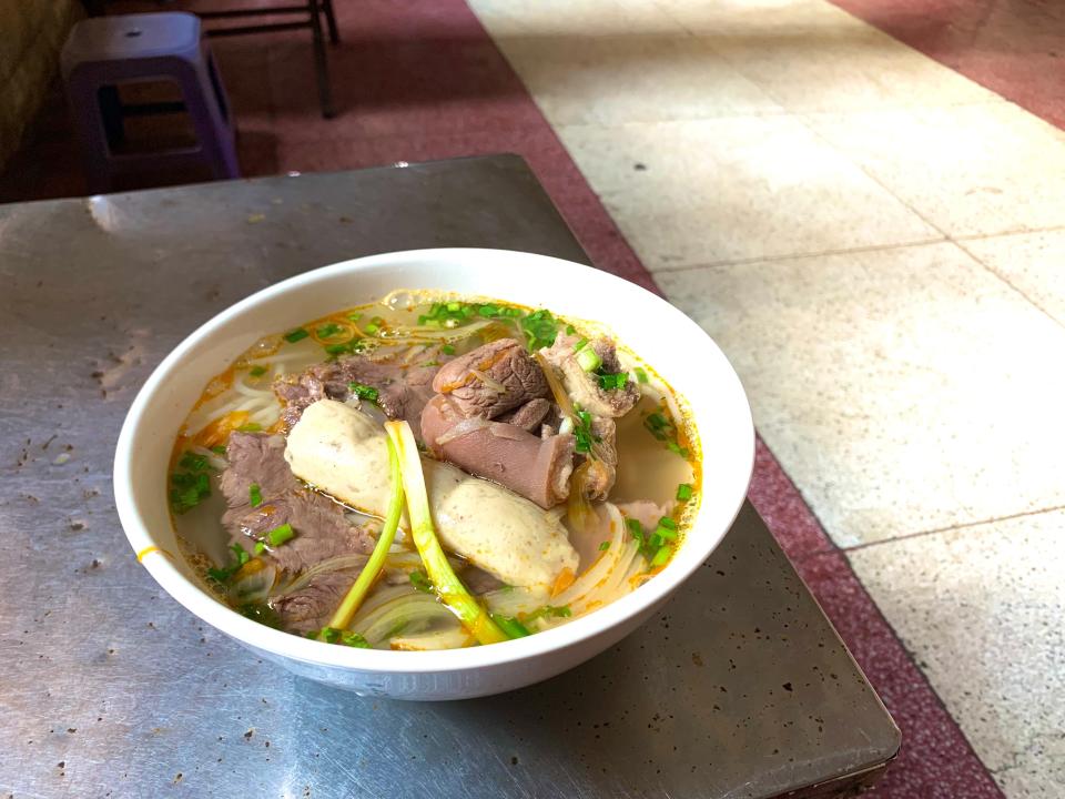 A bowl of Vietnamese beef noodle soup on a silver dining table