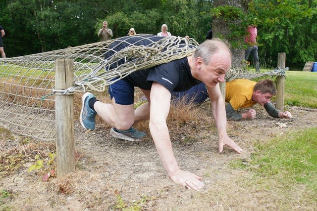 Sir Ed Davey emerges from beneath a lattice of rope at an assault course in Kent