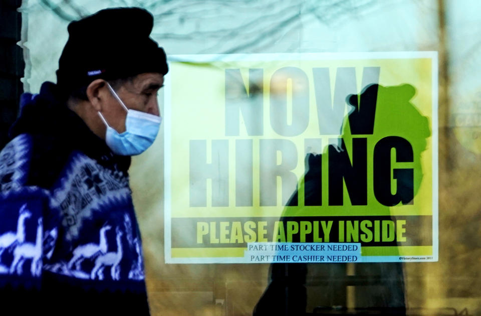 FILE - In this Nov. 28, 2020 file photo, a shopper wears a face mask and he walks past a store displaying a hiring sign in Wheeling, Ill. The number of Americans seeking unemployment benefits fell sharply last week but remained high by historical standards. Applications for benefits declined 111,000 from the previous week to a seasonally adjusted 730,000, the Labor Department said Thursday, Feb. 25. It is the lowest figure since late November. (AP Photo/Nam Y. Huh, File)