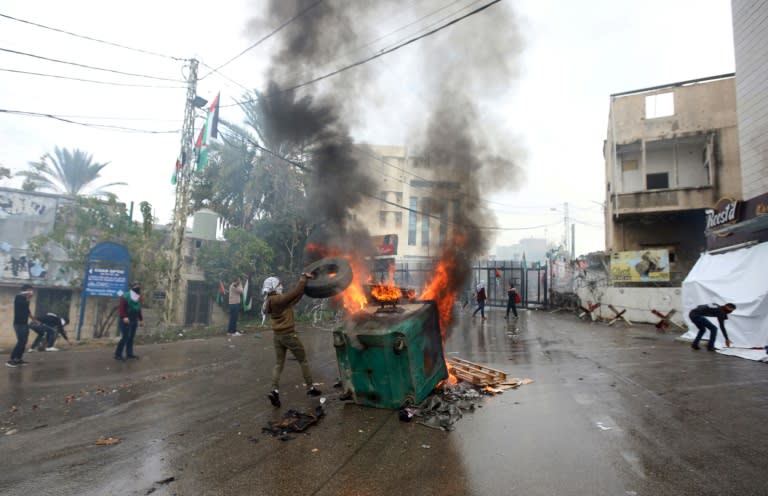 A protester throws a tire on a fire during a demonstration outside the US embassy in Awkar, on the outskirts of the Lebanese capital Beirut, on December 10, 2017