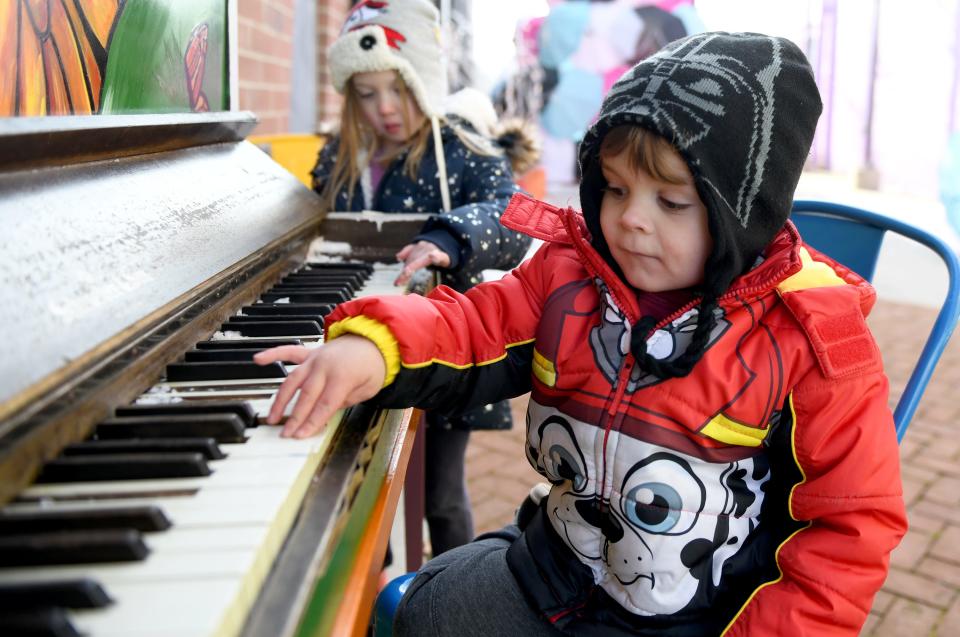 Roman Myers, 3, of East Canton plays the piano with an audiece of Reagan Pickens, 4, of East Canton, during a visit to Umbrella Alley in Louisville.  Wednesday, December 21, 2022.