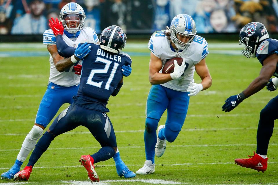 Tight end T.J. Hockenson of the Detroit Lions carries the football as wide receiver Marvin Jones, left, of the Detroit Lions blocks cornerback Malcolm Butler (21) of the Tennessee Titans during the second quarter of the game at Nissan Stadium on Dec. 20, 2020, in Nashville, Tennessee.