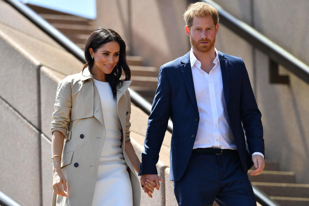 <p>Prince Harry and Meghan walk down the stairs of Sydneys iconic Opera in 2018</p> (AFP via Getty Images)