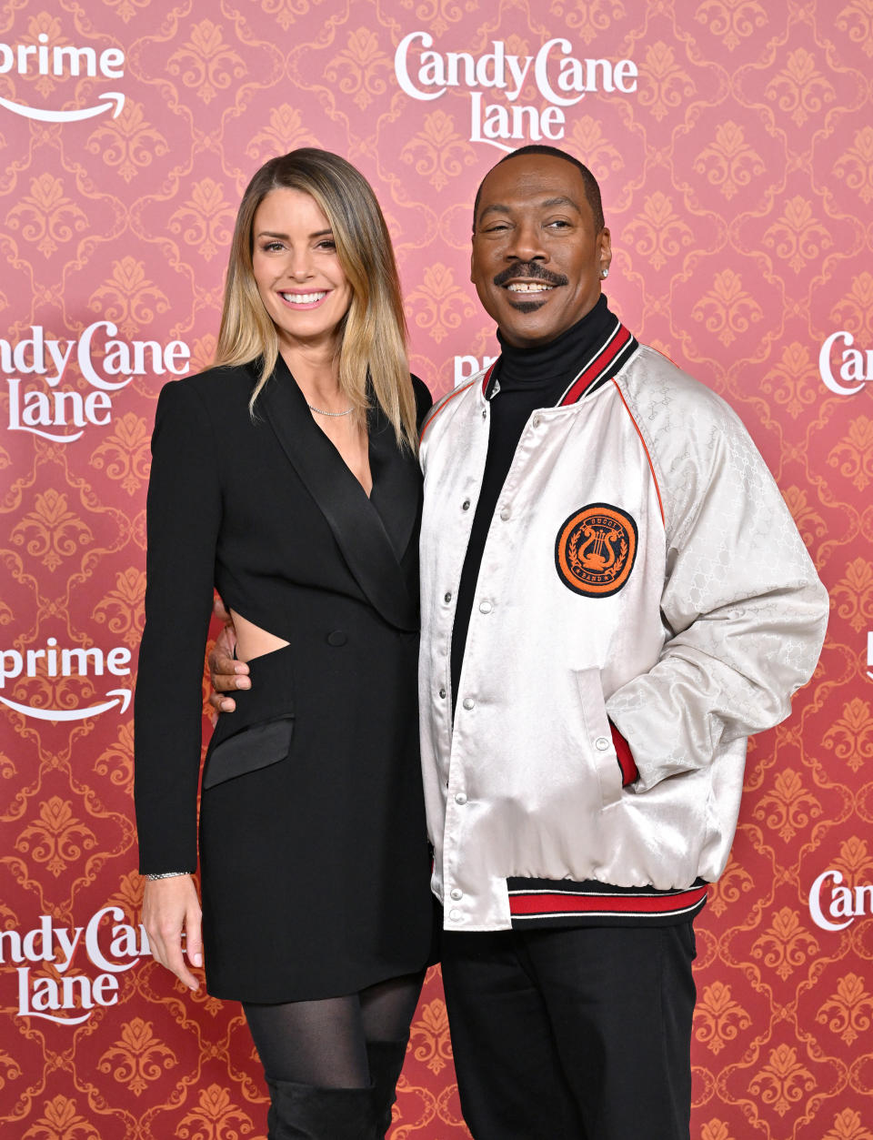 Two celebrities featured on the brand's background.A woman in a black dress and a man in a jacket with a logo