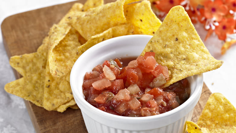 Chip dips in salsa bowl 