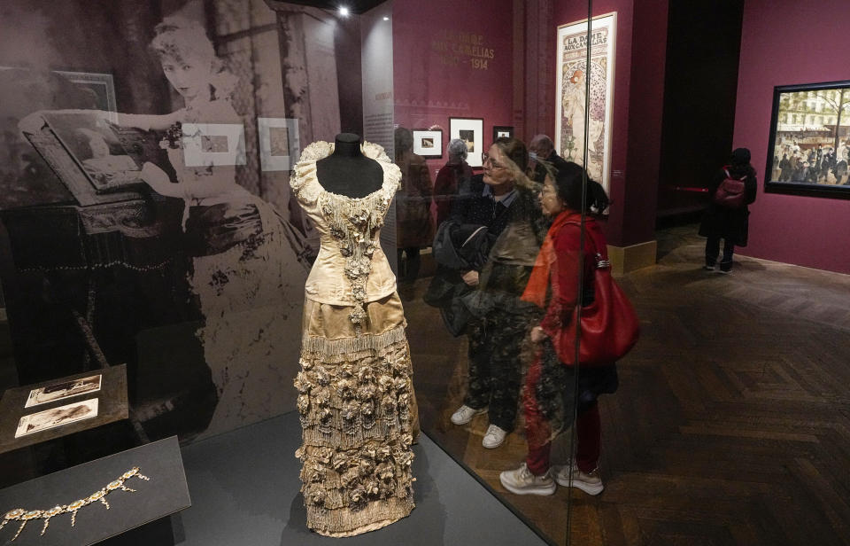 Visitors look at a dress worn by Sarah Bernhardt in the film "Froufrou" in 1880 as part of the "Sarah Bernhardt, and the woman created the star" exhibition at the Petit Palais museum in Paris, Friday, April 28, 2023. Inside Paris’ Petit Palais museum, the public is now discovering the madcap jigsaw puzzle of gothic stories, costumes, recordings, films, photos, jewels, sculptures, and personal objects for the first time together that made the unclassical beauty the object of fascination from Berlin, to London and New York. (AP Photo/Michel Euler)