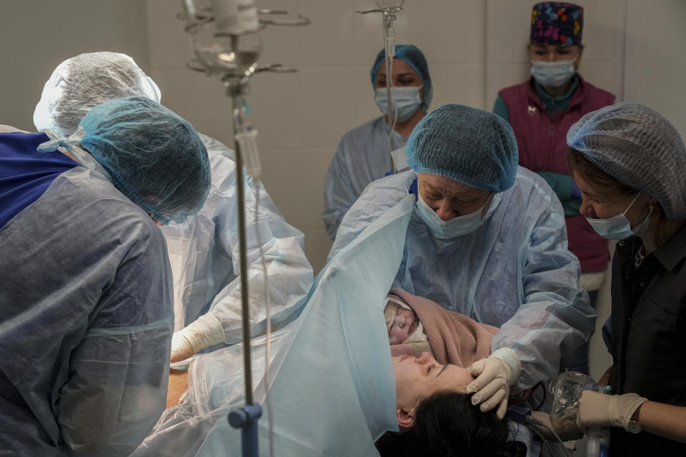 Medical workers hold a newborn girl Alana close to her mother after a cesarian section at a hospital in Mariupol, Ukraine, Friday, March 11, 2022. Alana's mother had to be evacuated from another maternity hospital and lost some of her toes after it was shelled. (AP Photo/Evgeniy Maloletka)