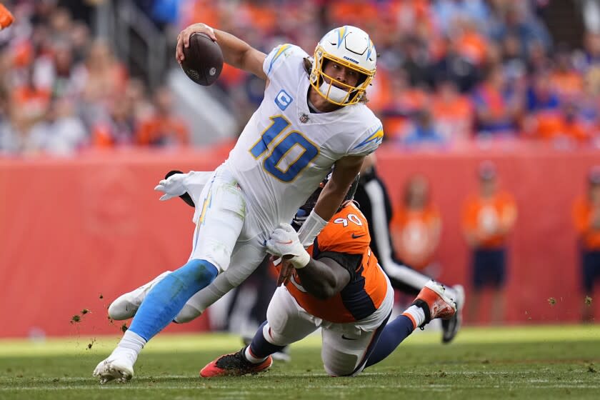 Los Angeles Chargers quarterback Justin Herbert (10) is hit by Denver Broncos defensive end DeShawn Williams.