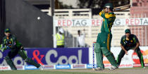 South African batsman Quinton de Kock (C) plays a shot as Pakistani wicket keeper Umar Akmal (L) looks on during the fifth and final day-night international at Sharjah Cricket Stadium in Sharjah on November 11, 2013. South Africa lead the five-match series 3-1. AFP PHOTO/Asif HASSAN