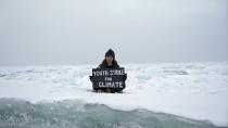 Environmental activist and campaigner Mya-Rose Craig holds a cardboard sign reading “youth strike for climate” in the middle of the Arctic Ocean