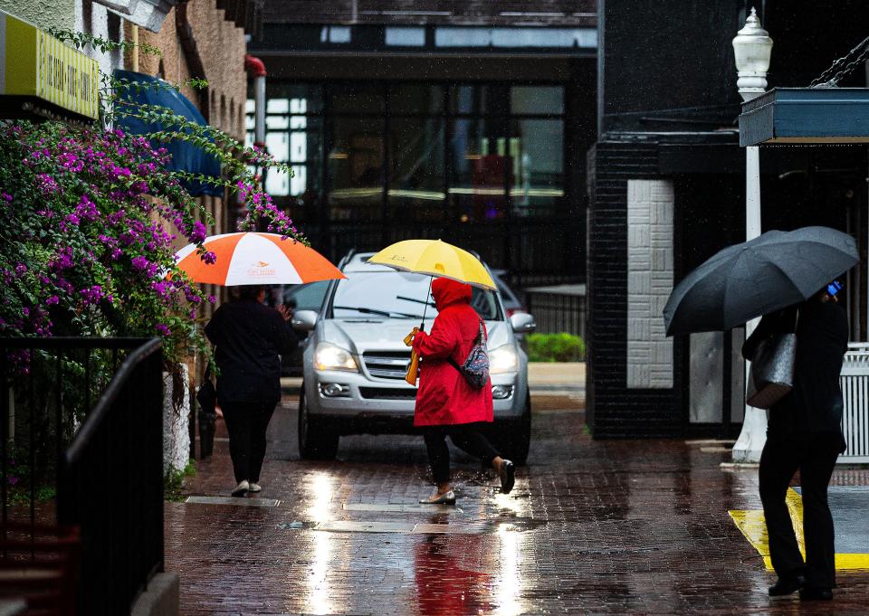 Pedestrians stroll through downtown Fort Myers as rainfall from two interacting low pressure systems drench the area on Wednesday, Nov. 15, 2023.