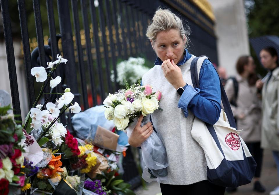 A person holds a floral tribute in front of Buckingham Palace, following the passing of Queen Elizabeth (REUTERS)