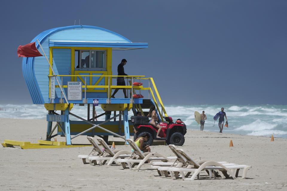 A lifeguard keeps his eye on surfers and swimmers in waves churned up by Tropical Storm Laura, Monday, Aug. 24, 2020, in Miami Beach, Fla. Tropical Storm Marco began falling apart Monday, easing one threat to the Gulf Coast but setting the stage for the arrival of Laura as a potentially supercharged Category 3 hurricane. (AP Photo/Wilfredo Lee)