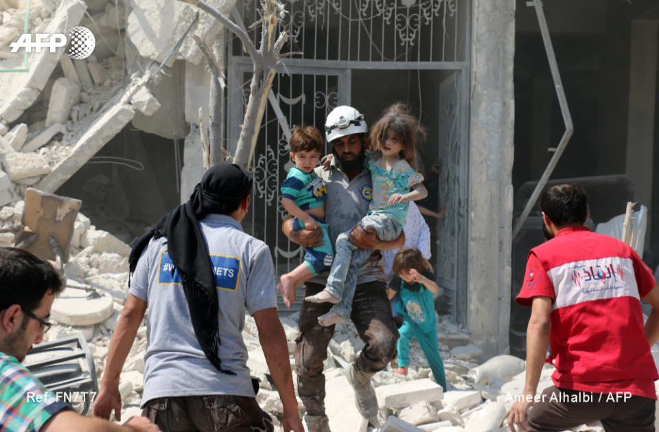 <span>Des civils syriens et un secouriste évacuent des enfants dans l'est d'Alep après un bombardement, le 27 août 2016 (AFP/Ameer al-HALBI)</span>