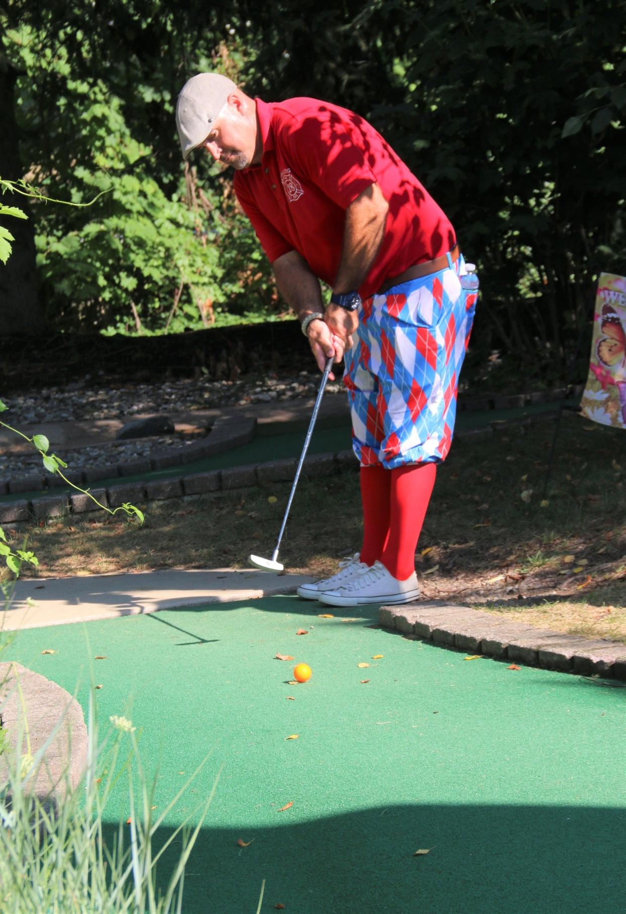 Firefighter/EMT Josh Tamulen takes a stroke at a mini golf competition between the town's firefighters and police.