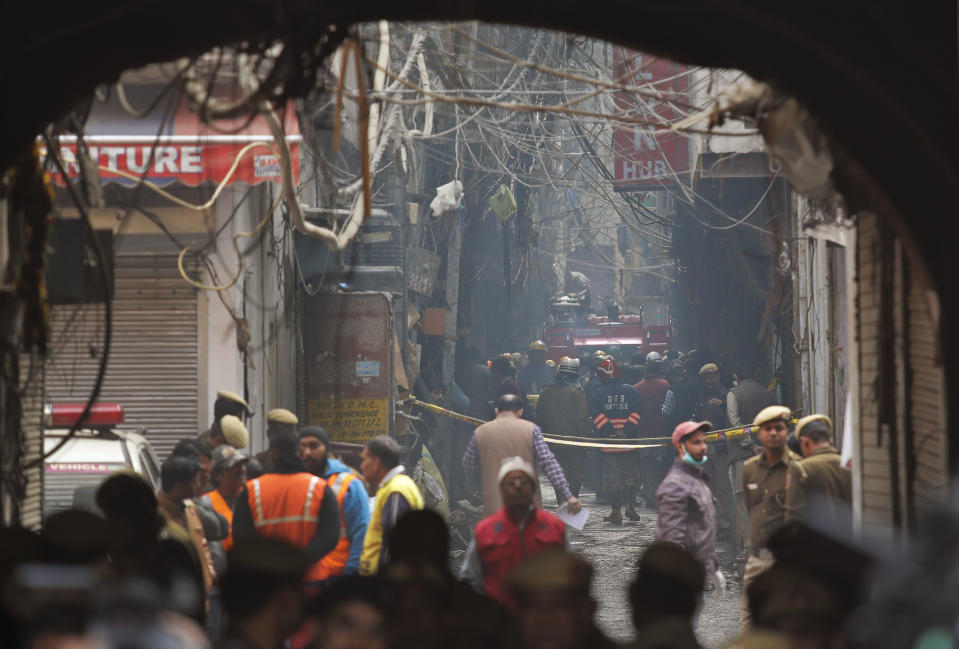 A fire engine stands by the site of a fire in an alleyway, tangled in electrical wire and too narrow for vehicles to access, in New Delhi, India, Sunday, Dec. 8, 2019. Dozens of people died on Sunday in a devastating fire at a building in a crowded grains market area in central New Delhi, police said. (AP Photo/Manish Swarup)