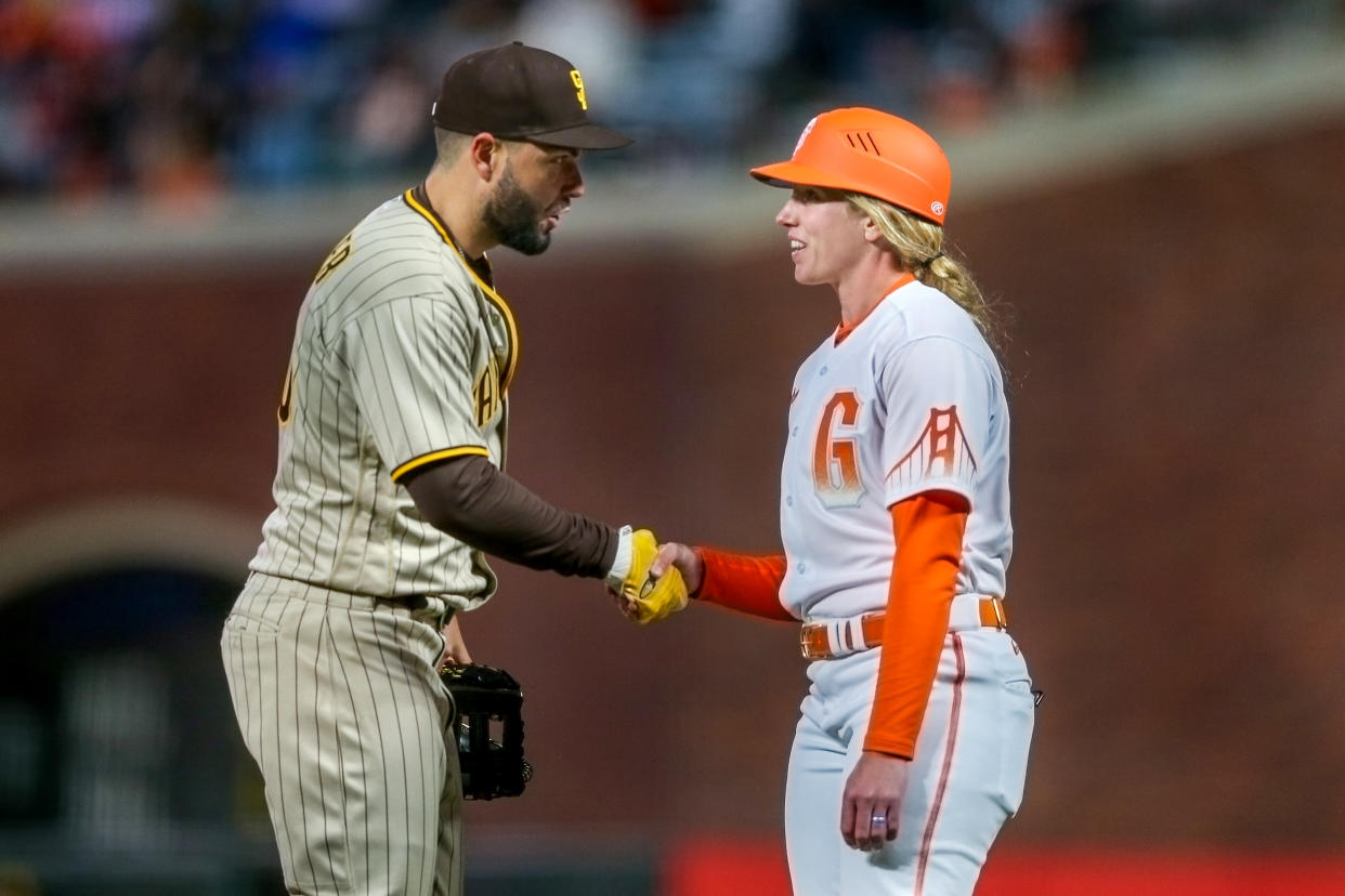 SAN FRANCISCO, CALIFORNIA - Eric Hosmer de los San Diego Padres (30) saluda a la coach de primera base de los San Francisco Giants Alyssa Nakken en la cuarta entrada del partido de MLB en el Oracle Park en San Francisco, California el martes 12 de abril de 2022. Nakken hizo historia como la primera mujer en ser coach en el terreno durante un juego de temporada regular. (Foto de Ray Chavez/MediaNews Group/The Mercury News via Getty Images)