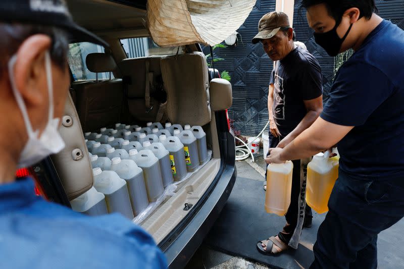 FILE PHOTO: Residents prepare containers of cooking oil to be distributed to locals at a filling station after stocks ran out in Jakarta