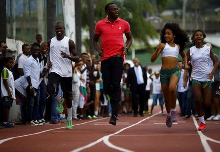 Jamaican Olympic gold medallist Usain Bolt (C) runs with youths at the Mangueira slum Olympic center, ahead of the "Mano a Mano" challenge, a 100-meter race, in Rio de Janeiro, Brazil, April 16, 2015. REUTERS/Ricardo Moraes/File Photo