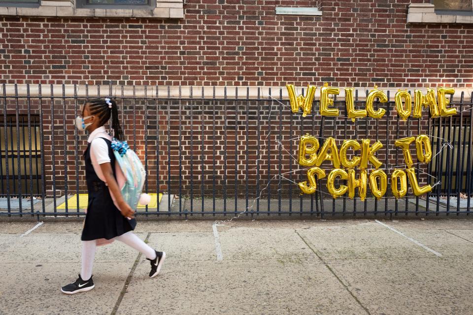 FILE - In this Sept. 13, 2021, file photo, a girl passes a "Welcome Back to School" sign as she arrives for the first day of class at Brooklyn's PS 245 elementary school in New York. COVID-19 deaths and cases in the U.S. have climbed back to where they were over the winter, fueled by children now back in their classrooms, loose mask restrictions and low vaccination levels.