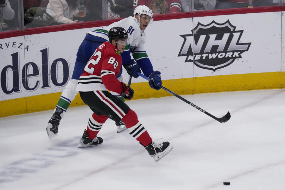 Vancouver Canucks center Dakota Joshua, top, passes the puck against Chicago Blackhawks defenseman Caleb Jones during the second period of an NHL hockey game in Chicago, Sunday, March 26, 2023. (AP Photo/Nam Y. Huh)