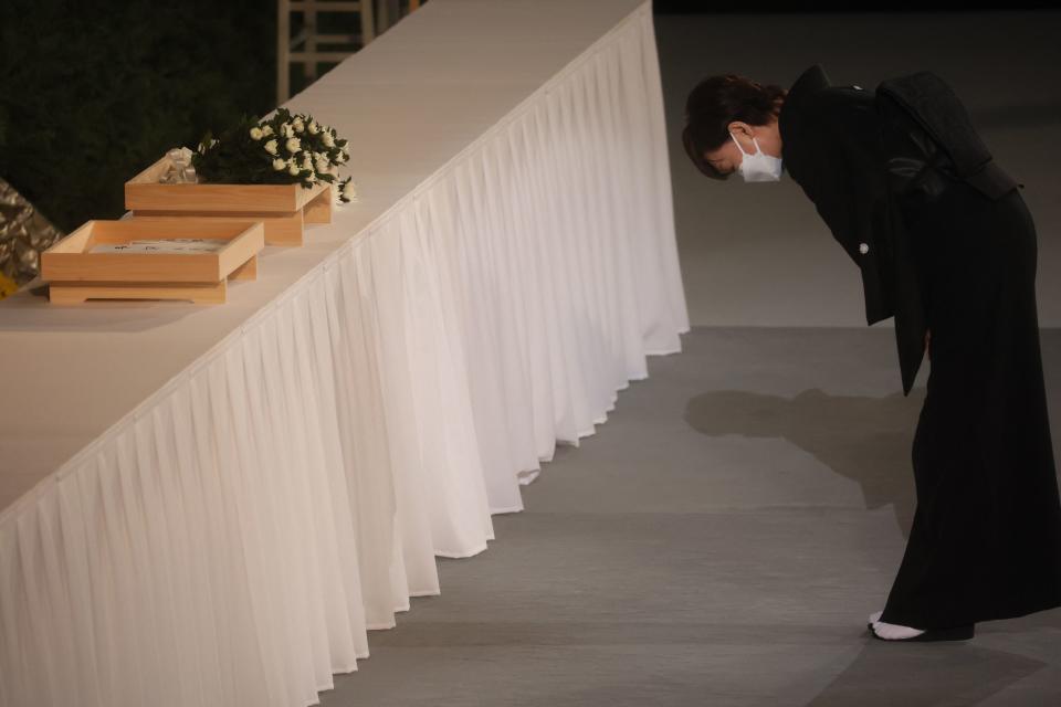 安倍昭惠捧著亡夫骨灰，隨著日本首相岸田文雄走入國葬會場。（AFP）