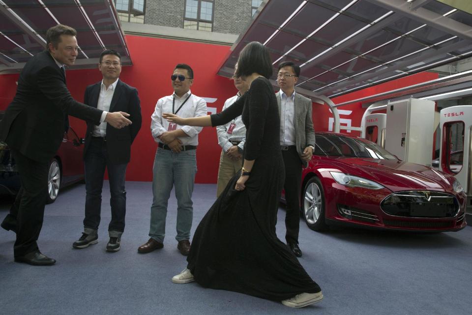 Tesla Motors CEO Elon Musk, left, greets the first customers of the company's Model S sedans at an event in Beijing, China, Tuesday, April 22, 2014. Tesla Motors Inc. delivered its first eight electric sedans to customers in China on Tuesday and Musk said the company will build a nationwide network of charging stations and service centers as fast as it can. (AP Photo/Ng Han Guan)