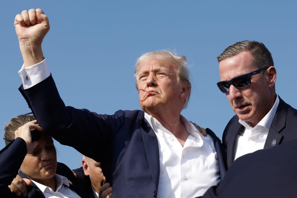 Republican presidential candidate former President Donald Trump pumps his fist as he is rushed offstage during a rally on July 13, 2024, in Butler, Pennsylvania