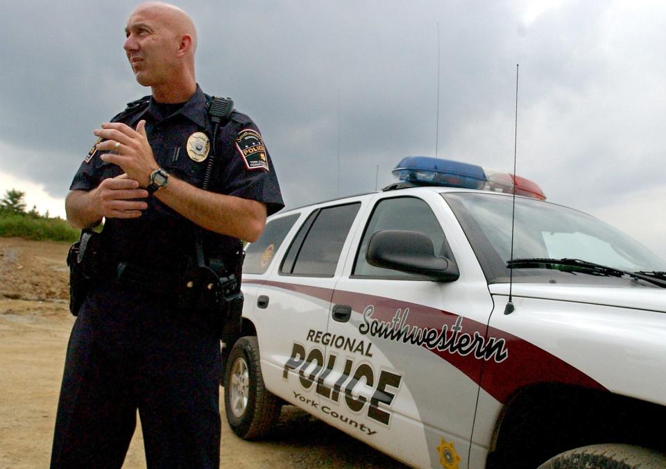In this file photo from July 15, 2003, former Southwestern Regional Police Officer Stu Harrison is pictured standing in front of a police vehicle.