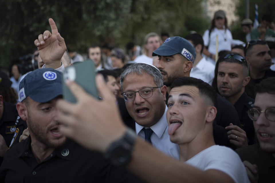 An Israeli takes a selfie with the Israel's National Security Minister Itamar Ben-Gvir, center, as he arrives at the Damascus Gate of Jerusalem's Old City during a march marking Jerusalem Day, an Israeli holiday celebrating the capture of east Jerusalem in the 1967 Mideast war, Wednesday, June 5, 2024. Thousands of mostly ultranationalist Israelis take part in an annual march through a sensitive Palestinian area of Jerusalem, with some stoking already surging wartime tensions by chanting "Death to Arabs." (AP Photo/Leo Correa)