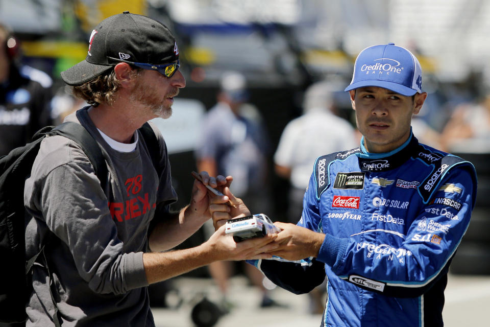 FILE - In this July 20, 2018, file photo, NASCAR Cup Series driver Kyle Larson signs an autograph for a fan wearing a Martin Truex Jr. shirt before auto racing practice at New Hampshire Motor Speedway in Loudon, N.H. Kyle Larson was fired Tuesday, April 14, 2020, by Chip Ganassi Racing, a day after nearly every one of his sponsors dropped the star driver for using a racial slur during a live stream of a virtual race. Larson, in his seventh Cup season with Ganassi and considered the top free agent in NASCAR mere weeks ago, is now stunningly out of a job in what could ultimately be an eight-figure blunder by the star. (AP Photo/Mary Schwalm, File)