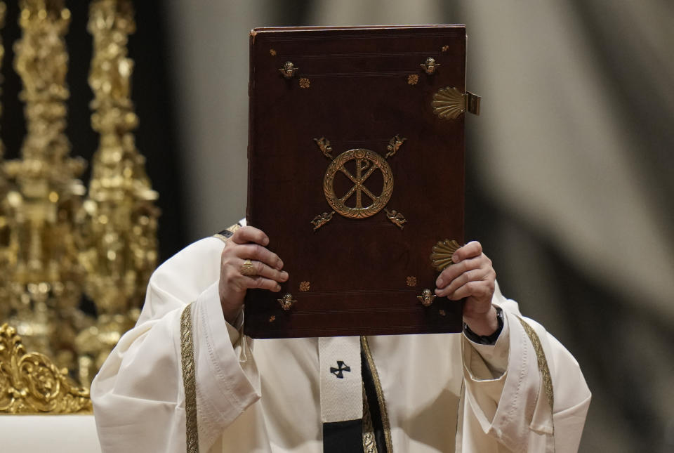 Pope Francis holds the book of Gospels as he celebrates Christmas Eve Mass, at St. Peter's Basilica, at the Vatican, Friday Dec. 24, 2021. Pope Francis is celebrating Christmas Eve Mass before an estimated 1,500 people in St. Peter's Basilica. He's going ahead with the service despite the resurgence in COVID-19 cases that has prompted a new vaccine mandate for Vatican employees. (AP Photo/Alessandra Tarantino)