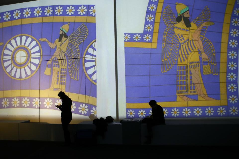 Visitors look on in the Palmyra Exhibit, a three-dimensional projection featuring never-before-seen images of Palmyra taken by a drone in April after the city was liberated from IS fighters, at Grand Palais in Paris, Tuesday, Dec.13, 2016. As Islamic State extremists recapture the ancient Syrian city of Palmyra, the French president and the UNESCO chief are inaugurating an exhibit in Paris to educate the public about the wonders of endangered UNESCO heritage sites in Palmyra and the Middle East. (AP Photo/Francois Mori)