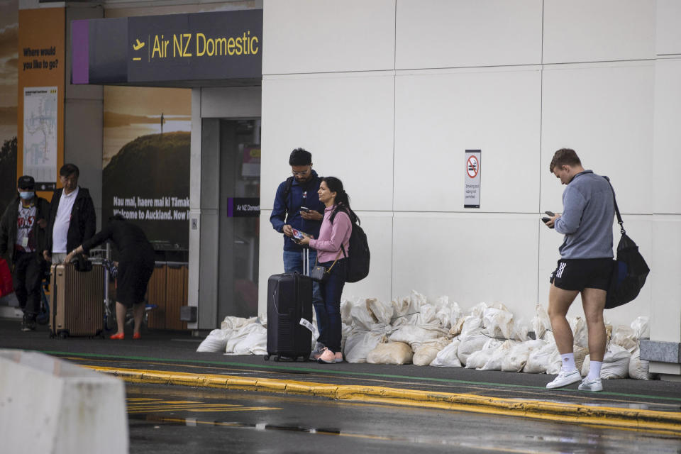 Passengers wait outside Auckland Airport after flights were canceled and passengers stranded as a cyclone hit the northern parts of New Zealand, Sunday, Feb. 12, 2023. New Zealand's national carrier has canceled dozens of flights as Aucklanders brace for a deluge from Cyclone Gabrielle, two weeks after a record-breaking storm swamped the nation's largest city and killed several people. (George Heard/NZ Herald via AP)